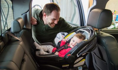 A father safely buckles his daughter into her rear facing car seat. (Credit: North Dakota DOT)