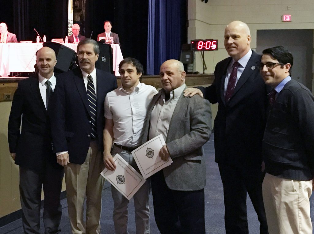 Assistant TR North Wrestling coaches Josh Huber and John DeMarco (center) are honored by district officials for their role in saving a student's life during a wrestling match. (Photo: Daniel Nee)
