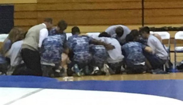 Wrestlers pray during a match where a teammate, Brandon Gonzalez, went into cardiac arrest. (Credit: Stephen Glawson)